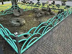 A fenced off area containing large stones, each with a single cylindrical hole