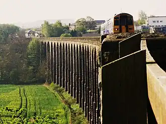 A train traversing a long stone viaduct
