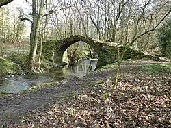 An arched stone bridge over a small beck