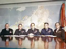 A group of five men in military uniform seated at a table