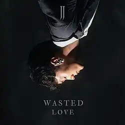 The cover artwork for "Wasted Love". The cover features an upside-down photo of JJ looking downwards amongst a black background.