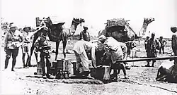 Three soldiers look on while Egyptian workers fill a water fantasie from a pipe