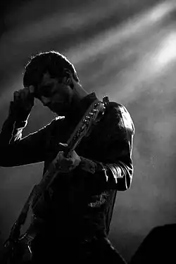 a black and white photo of James Likeness playing a bass on stage