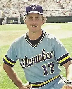 A man in a powder blue baseball jersey with "Milwaukee" written across the chest and a blue cap kneeling on a baseball field