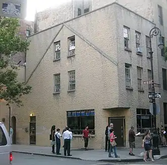 The Julius Bar Building, a gray stucco-faced building, as seen from across the street. There are people on the sidewalk in front of the bar.