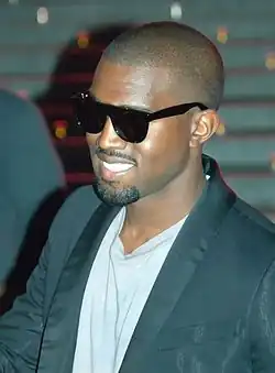 A man dressed in a white shirt and black suit wearing sunglasses.