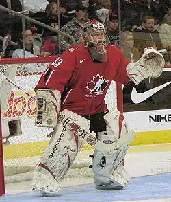 Woman wearing red hockey uniform and face mask