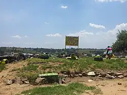 A community painted sign, reading "Kya Sands Formal Settlement, Please RDP"