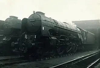 Steam locomotive with four small carrying wheels at the front, six large driving wheels, two small carrying wheels below the cab, and a tender