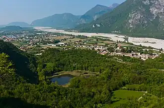 A body of water surrounded by greenery and a human settlement in the distance.