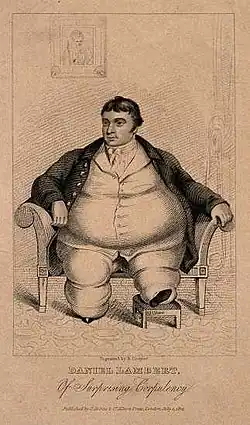 Smartly dressed fat man with dark hair sitting on a chair