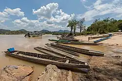 Beach of Don Khon, a sunny day with children running on the river bank, where several pirogues are attached.