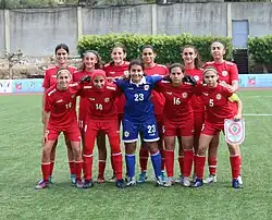 Lineup of eleven players of the Lebanon women's national under-20 football team. The outfield players are wearing red kits, and the goalkeeper is wearing a blue kit.
