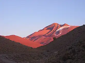 A mountain glows red above a shaded valley