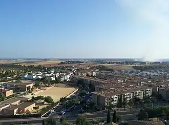 View of Mairena del Aljarafe, with a road, buildings and a smoke column on the right