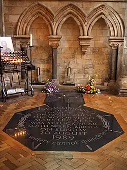 Black marble memorial set into the floor that reads: "In remembrance of all those who drowned when the motor vessel Marchioness was struck near Southwark Bridge on Sunday 20 August 1989. Many waters cannot quench love"