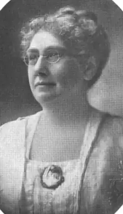 An older white woman with grey hair in an updo, wearing glasses