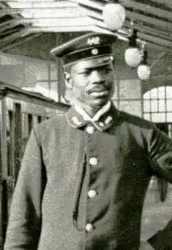Martin Dibobe wearing a train driver uniform with hat in a Berlin U-Bahn station