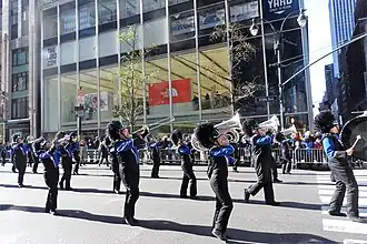 The building's facade as seen from across Fifth Avenue in 2017. A parade is crossing in front of the photographer.