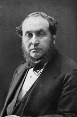 photograph of middle-aged man with bushy sideboards facing spectator, in jacket, waistcoat and bowtie
