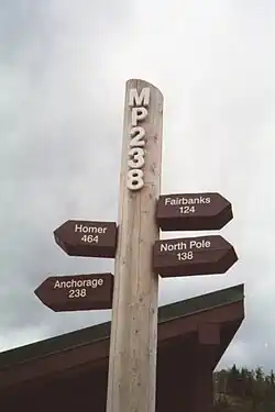 Milepost 238 signpost in McKinley Park. The signpost is located in a turnout adjacent to a bridge crossing the Nenana River and near the entrance to Denali National Park.