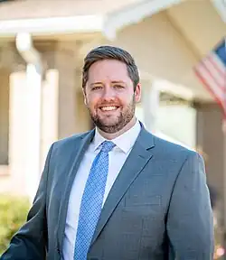 Photo of smiling man with beard in grey suit