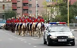 A mounted cavalry unit of the guard being escorted by local police during a procession to Naadam.