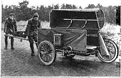 Stretcher being loaded into a motorcycle sidecar by two men.