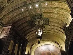 The general reception room behind the auditorium, which has an arched ceiling. There is a mural on the wall in the rear.
