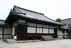 Wooden building with a hip-and-gable roof and white walls.