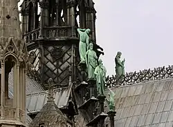 Three apostles with St. John's eagle in the foreground. St. Thomas has his back turned, as he inspects the spire.