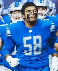 Penei Sewell from the waist up in a Detroit Lions jersey with his face painted
