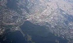 Aerial view of Penzing with Otto-Wagner-Spital near the top of the photo (three rows of big buildings), square-shaped Gerhard Hanappi Stadium downwards from it, and Baumgarten between them, with its sizable Baumgartner Cemetery.