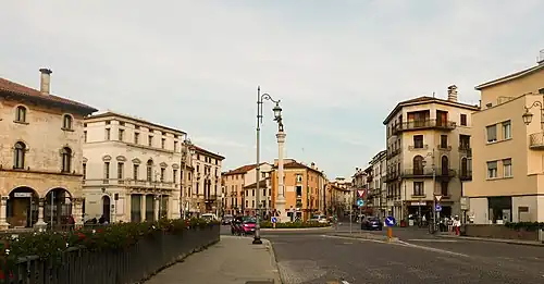 View across Piazza XX Settembre towards buildings, with a central column topped by a statue.
