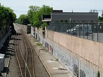 Asphalt platforms in a trench, with a one-story building in the background