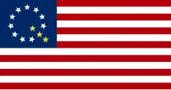 A modified version of the American flag with ten white stars and three gold stars forming a letter Q in the canton