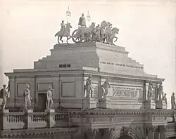 A tiered roof with a statue of four horses pulling a chariot on top