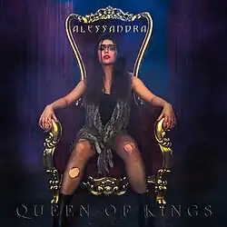 The cover artwork for "Queen of Kings". The artwork features Alessandra in torn fishnet stockings, a black shirt, and a scarf sitting on a throne amongst a blue and purple background.