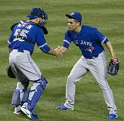 Roberto Osuna and catcher Russell Martin celebrate Osuna's 20th save of the 2015 season on the field.