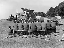 Apprentices of No. 1 School of Technical Training listen to a lecture on servicing aircraft in the field, in front of a line of instructional airframes, during the early 1940s.