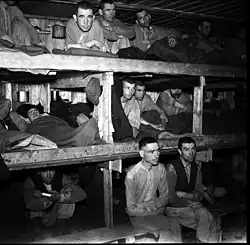 Unsmiling men, crowded into three-tier bunks