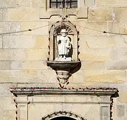 A niche with a white statue of Saint James. Under it, the top of a gate is visible. On it is engraved "YGLESIA DE REFVGIO"