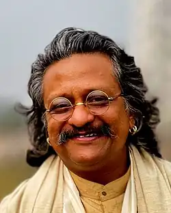 close-up of Sattyakee D'com Bhuyan wearing light-coloured, traditional Indian clothing, grinning directly at camera