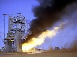 Large test stand during a hot firing: depicts large exhaust flume exiting the side of the test stand.