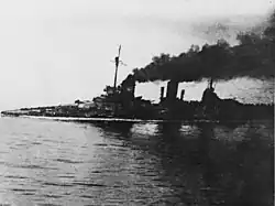 A large gray warship, heavily flooded; its deck is nearly submerged. Thick black smoke pours from the funnels. An in-photo caption reads: "Seydlitz nach der Skaggerack-schlacht", or "Seydlitz after the Skaggerak battle."
