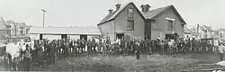 Photo of man in suit in front of horses and barn