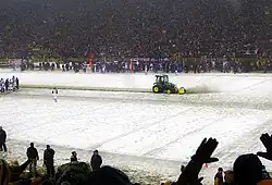 A snowy field with a tractor clearing snow in the middle