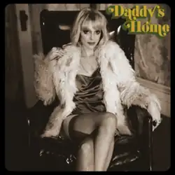 Sepia-toned image of St. Vincent sitting in a leather chair, wearing a short dress, ripped tights, white fur coat and blonde wig