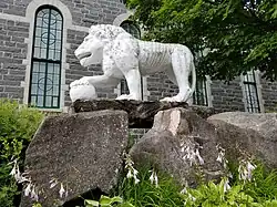 Cement lion on the north-east side of the church of Sainte-Thècle fashioned by the priest Maxime Masson.