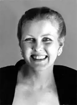 portrait of a caucasian female aged around 40 years, with a cheesy grin, hair tied in a bun